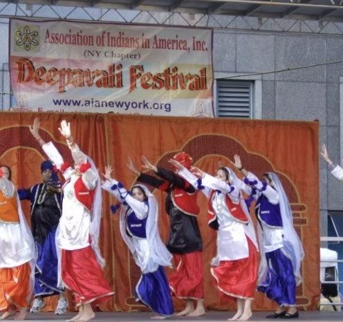 Dancers in Bhangra costumes performing on stage at the Association of Indians in America Deepavali Festival
