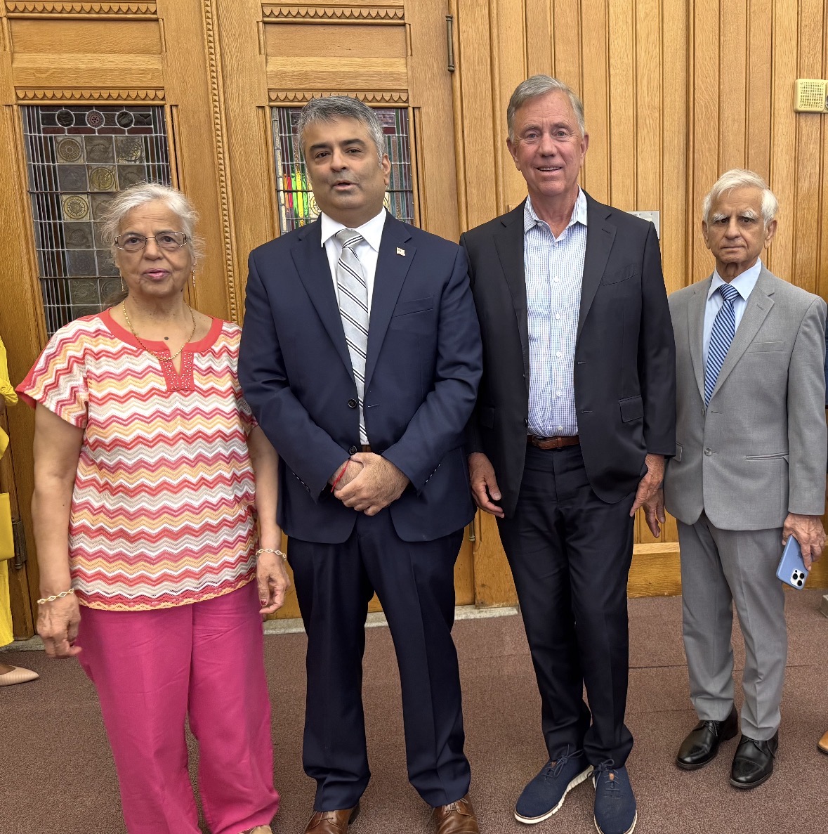 Rajeev Pahuja and Governor Ned Lamont with two family members in front of wooden doors