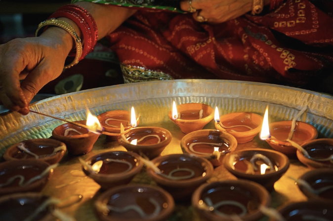 Clay diya oil lamps being lit for Diwali